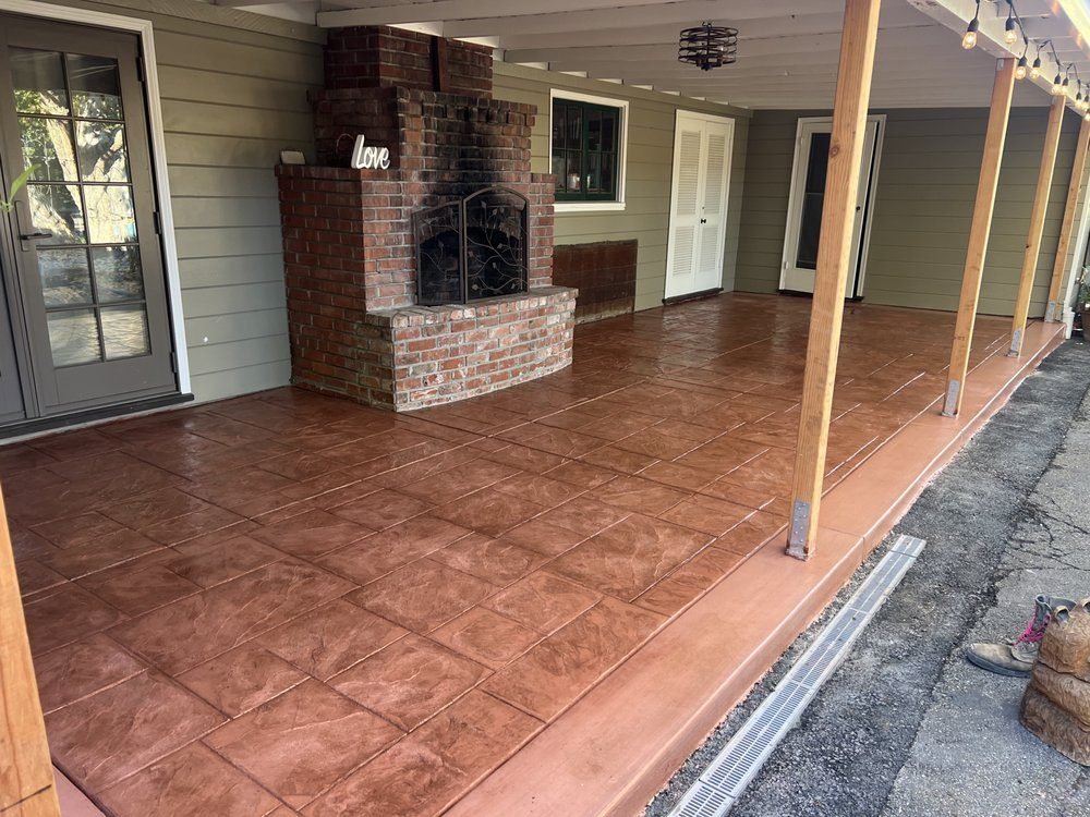 Stained terracotta-toned covered porch floor beside a brick fireplace