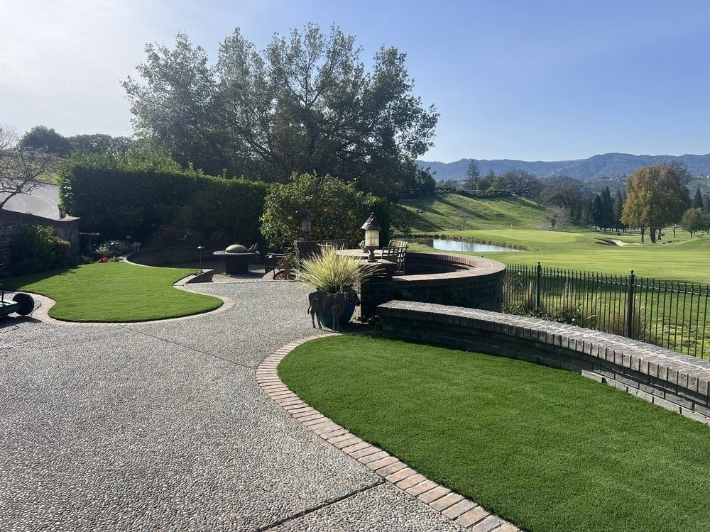 Curved exposed aggregate path with a brick edge beside artificial turf