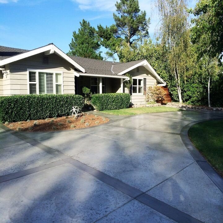 Concrete driveway with a darker contrast band curving beside a lawn